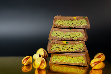  Tower of pistachio chocolate bars with nuts around, perfect for sweet product advertising, packaging, or social media campaigns.