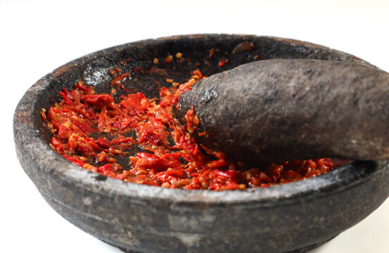 Sambal or traditional chili sauce from Indonesia, freshly made using stone mortar and pestle. Flat lay or top view. Isolated in white background