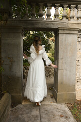Full length female figure of beautiful blonde model wearing white fantasy wedding gown.  walking through doorway of historical  fairytale castle location 