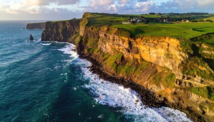 Dramatic coastal cliffs meet a turbulent ocean under a golden sunset sky with green grassy tops and a distant village