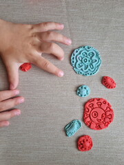 Covid and other respiratory virus molecules made of plasticine. Little toddler education moment in a playful mode. Bacteria made of playdough and kids' hands over the table. 