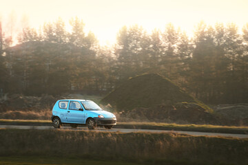 Fototapeta premium Subcompact hatchback driving in rural scenery