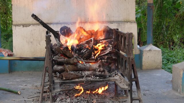Hindu outdoor funeral pyre burning on wooden bier at rural cremation ground in India