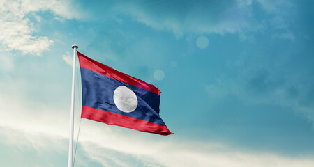 Laos national flag fluttering. The flag blowing in beautiful soft sky. Laos national flag for independence day.