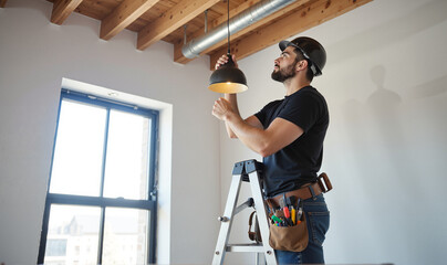 Professional Handyman Installing Ceiling Light – Male Electrician on Ladder Working with Electrical Fixture for Home Improvement Projects, Residential Maintenance, and International Men's Day Campaign