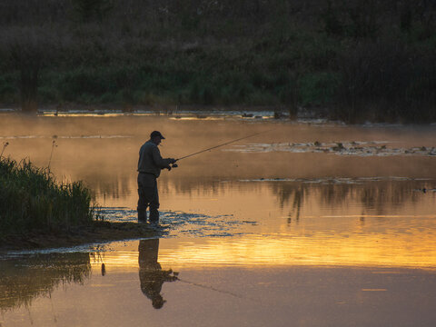 man fishing on the river at sunrise - Powered by Adobe
