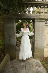 Obraz premium Full length female figure of beautiful blonde model wearing white fantasy wedding gown. walking through doorway of historical fairytale castle location 