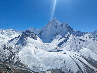 Snow-covered mountains tower majestically against a vibrant blue sky showcasing nature's beauty. Himalayan Mountains, Nepal. Everest base camp