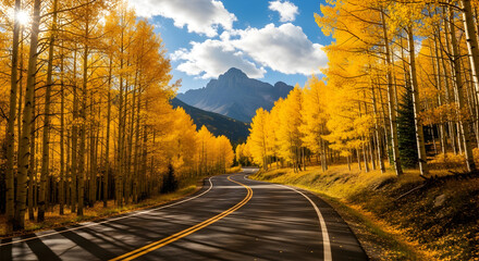 Experience the stunning beauty of autumn with winding roads through vibrant golden aspen trees leading to majestic mountains under a bright blue sky with fluffy clouds