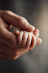 A touching closeup of a newborns tiny hand gripping a larger adult finger. Symbolizes love, care, trust, family, and new beginnings. Ideal for parenting, healthcare, and emotive themes.