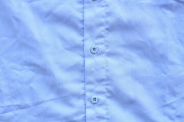 Close up of a textured white shirt with buttons attached