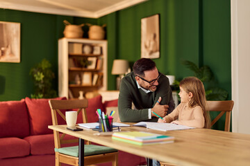 Dad Helps Daughter With Homework At Cozy Green Living Room Table For Family Study