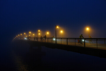 Radfahrer bei Dunkelheit im Nebel auf einer Br&uuml;cke