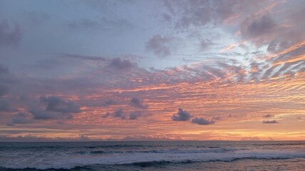 Vibrant sunset over the ocean with dramatic pink and orange altocumulus clouds creating a breathtaking, beautiful, and peaceful natural scene