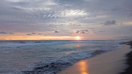Vibrant sunset over the ocean with dramatic pink and orange altocumulus clouds creating a breathtaking, beautiful, and peaceful natural scene
