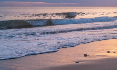 Gentle waves at sunset on a beach. Soft pink and purple hues