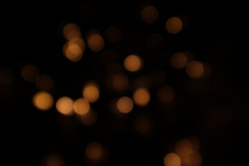 Obraz premium Golden blurred bokeh lights on black background. Glitter sparkle stars for celebrate. Overlay for your design. Bokeh effect golden light background. Golden Christmas concept. yellow sparkling bokeh