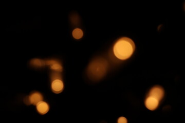Golden blurred bokeh lights on black background. Glitter sparkle stars for celebrate. Overlay for your design. Bokeh effect golden light background. Golden Christmas concept. yellow sparkling bokeh