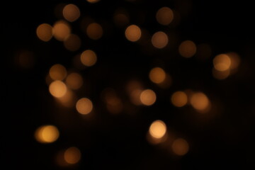 Golden blurred bokeh lights on black background. Glitter sparkle stars for celebrate. Overlay for your design. Bokeh effect golden light background. Golden Christmas concept. yellow sparkling bokeh