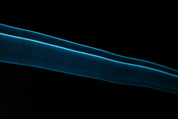 Abstract blue light trails on dark background, long-exposure swirling motion lines for technology...