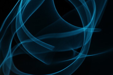 Abstract blue light trails on dark background, long-exposure swirling motion lines for technology...