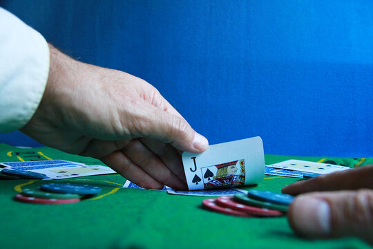 Mano de cartas de jugador y apostante de poker sobre tapete de casino con fichas de juego