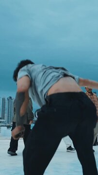 Hispanic hipster dancing surrounded by multicultural friend at city view with blue sky. Group of street dancer performing at rooftop. Active, fun, happy atmosphere. Outdoor sport 2024. hiphop.
