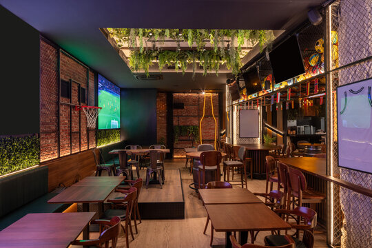 Sports lounge interior with brick walls, multiple TVs wood accents and ceiling plants