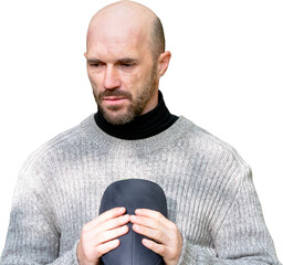 Pensive bald man with a beard in a gray sweater, looking down while holding a cap. Isolated on a transparent background, perfect for design elements requiring emotional depth and easy integration.