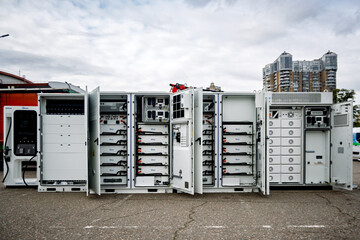 Ukraine, Kyiv - October, 16, 2025:Modular battery energy storage system (BESS) units with open doors revealing internal components and Deye batteries, set outdoors against a cloudy sky