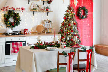Cozy Christmas kitchen interior with decorated tree, table, candles, and festive garland