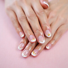 Female hands with gold detailed nail art, clean pastel background, luxury beauty concept.