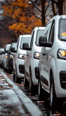 Canvas schilderij Voertuigen Fleet of cargo vehicles lined up on road with orange foliage and bare trees.  © Artsaba Family