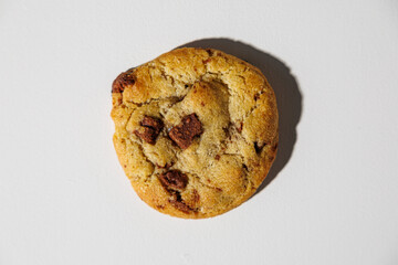 One golden-brown chocolate chip cookie sits centered on a clean white background, showcasing its soft texture and chunks of chocolate. No visible branding
