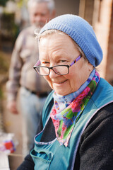 Elderly woman in apron smiling while working outdoors