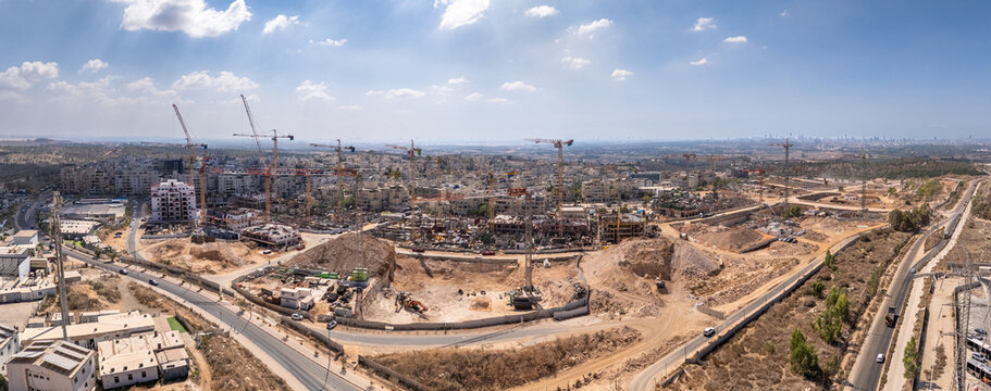 Aerial view of a sprawling construction site where cranes stand tall against a bright sky, marking new developments, El'ad, Center District, Israel.