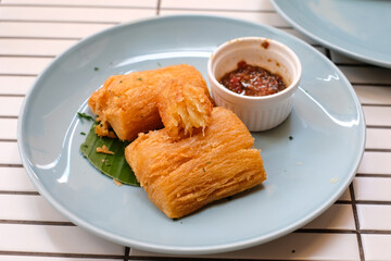 Golden fried cassava served on a light blue plate with white background. Perfect for restaurant menu design, tropical food promotion, or culinary asia traditional snacks.