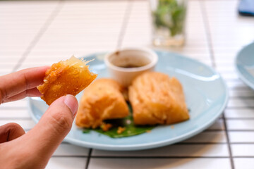 Golden fried cassava served on a light blue plate with white background. Perfect for restaurant menu design, tropical food promotion, or culinary asia traditional snacks.