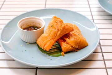 Golden fried cassava served on a light blue plate with white background. Perfect for restaurant menu design, tropical food promotion, or culinary asia traditional snacks.
