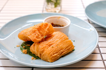 Golden fried cassava served on a light blue plate with white background. Perfect for restaurant menu design, tropical food promotion, or culinary asia traditional snacks.