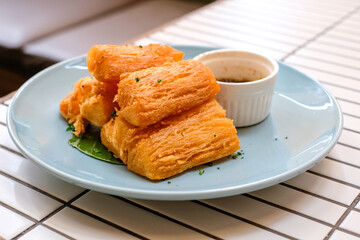 Golden fried cassava served on a light blue plate with white background. Perfect for restaurant menu design, tropical food promotion, or culinary asia traditional snacks.