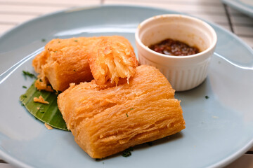Golden fried cassava served on a light blue plate with white background. Perfect for restaurant menu design, tropical food promotion, or culinary asia traditional snacks.