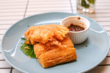 Golden fried cassava served on a light blue plate with white background. Perfect for restaurant menu design, tropical food promotion, or culinary asia traditional snacks.