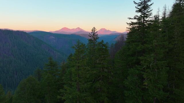 Drone footage of Oregon&rsquo;s Three Sisters volcanoes with light fading across fores