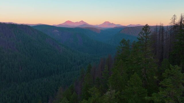 Aerial drone flight capturing Three Sisters and surrounding valleys at dusk