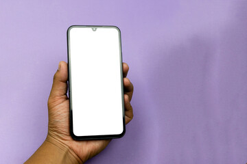 Hand holding a smartphone with a white screen on a purple background. Purple concept. White screen concept.