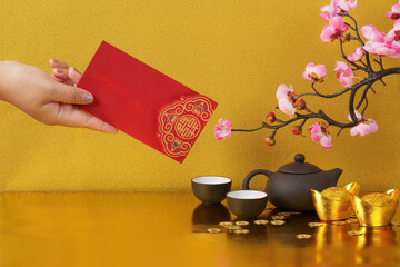Chinese New Year with red envelope and tea set on golden background