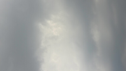 Overcast sky background filled with dense gray clouds, with a faint bright spot in the center...