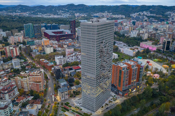 Naklejka premium Morning aerial view of Downtown One in Tirana, Albania, surrounded by autumn colors and modern city buildings.