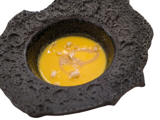 cream of zucchini soup with crispy topping, presented on an avant-garde luxury restaurant plate with a volcanic lava effect, closed shot. on a white background